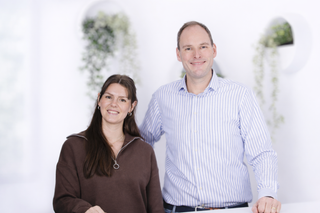 Laura & Christoph: Gründer der Unternehmens HEJLO - lächelnd vor hellem, modernen Hintergrund